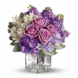 Purple and pink bouquet in a clear square vase