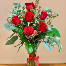 Red roses in a clear glass vase with pink filler flowers