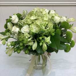 Green and white bouquet in a glass vase with ribbon