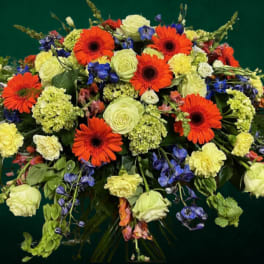 Large bouquet of orange gerbera daisies, pale roses, and blue flowers