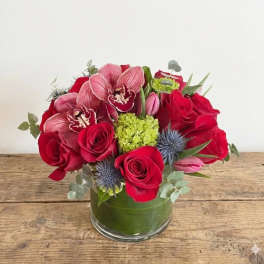 Red roses and pink orchids arranged in a glass vase