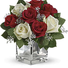Red and white roses arranged in a clear square vase