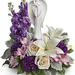 Purple and white floral arrangement with an angel figurine