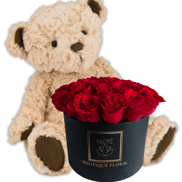 Teddy bear beside a black box of red roses