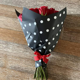 Bouquet of red roses wrapped in black polka-dot paper with a red ribbon