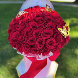 Round bouquet of red roses with butterfly accents and a red ribbon