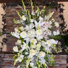 Tall white floral spray with lilies, roses, and daisies