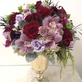 Bouquet of red and lavender flowers in a gold pedestal vase