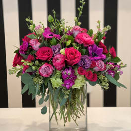 Pink and purple mixed flower arrangement in a clear glass vase
