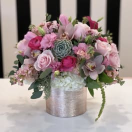 Pink floral arrangement in a silver vase with a succulent center