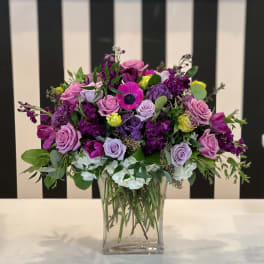 Mixed purple and pink flower arrangement in a clear glass vase