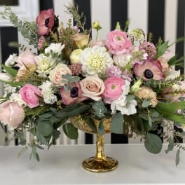 Pink and white mixed flower arrangement in a gold pedestal vase