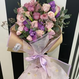 Bouquet of pink and purple flowers wrapped in pastel paper with a ribbon