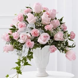 Pink roses and carnations arranged in a white vase