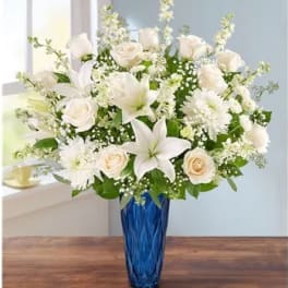 White roses and lilies in a blue glass vase