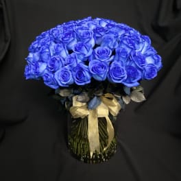 Blue rose bouquet in a glass vase with a gold ribbon