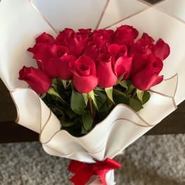 Bouquet of red roses wrapped in white paper with a red ribbon