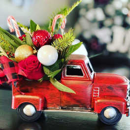 Red rose arrangement in a red toy truck with candy cane accents