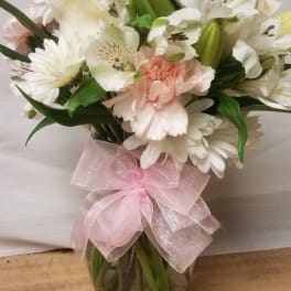White and pale pink bouquet in a glass vase with a pink ribbon