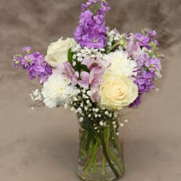 Bouquet of purple and white flowers in a clear glass vase