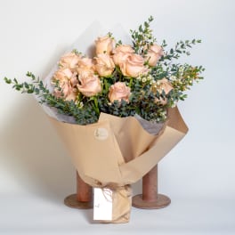 Bouquet of pale peach roses wrapped in tan paper