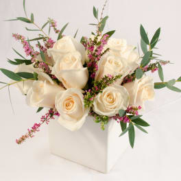 Cream roses with pink filler flowers in a white box vase