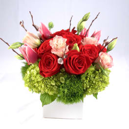 Red roses and pink tulips in a white square vase
