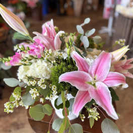 Pink lilies and white filler flowers in a white vase