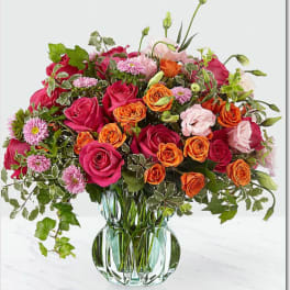 Mixed pink and orange roses in a clear glass vase