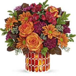 Bouquet of orange and red flowers in a patterned vase