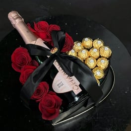 Heart-shaped gift box with red roses, champagne, and gold-wrapped chocolates
