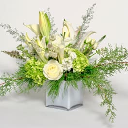 White lilies and roses in a square glass vase with green hydrangeas