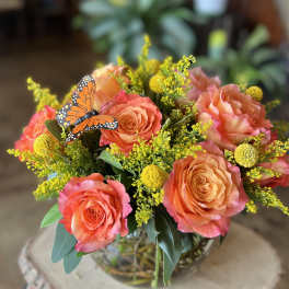 Bouquet of coral roses with yellow filler flowers in a glass vase