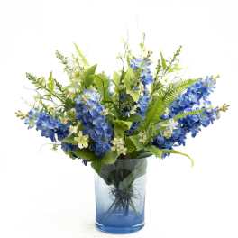 Blue hydrangea-like flowers in a glass vase with white filler blooms