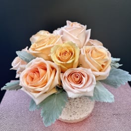 Peach and blush roses arranged in a small vase