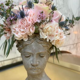Floral arrangement in a stone bust vase with pale pink and cream blooms