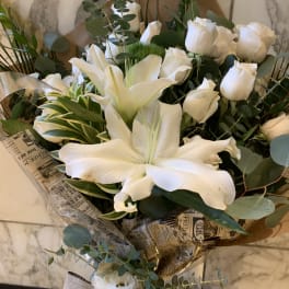 White lilies and roses in a wrapped bouquet with eucalyptus