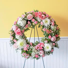 Pink and white floral wreath on a metal stand