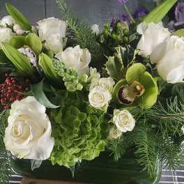 Long white floral arrangement with green orchids and roses