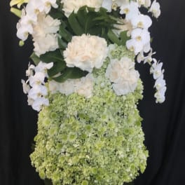 Tall floral arrangement with white orchids, lilies, roses, and green blooms