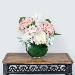 Pink and white flower arrangement in a round glass vase