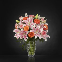 Pink lilies and orange roses in a clear glass vase