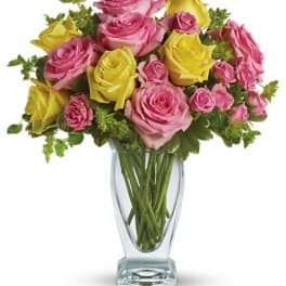 Pink and yellow roses arranged in a clear glass vase