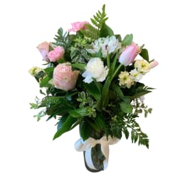 Pink and white bouquet in a clear glass vase with a white ribbon