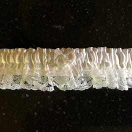 White lace and satin bridal garter on a dark surface