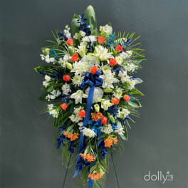 Large standing floral spray with white lilies, orange roses, and blue ribbon
