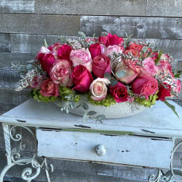 Pink and red rose arrangement in a white bowl vase