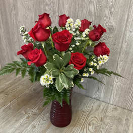 Red roses and white daisies arranged in a burgundy vase.