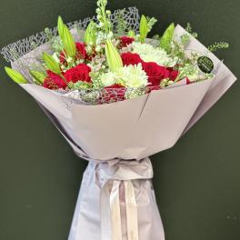 Bouquet of red roses and white lilies wrapped in pale paper
