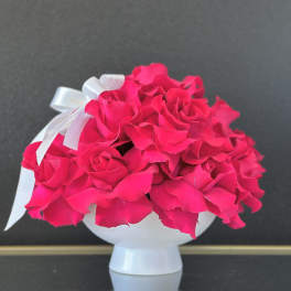 Bright pink rose bouquet in a white vase with a ribbon bow